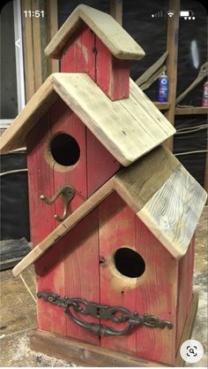 a red birdhouse with chains hanging from it's sides