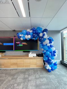 an office decorated with blue and white balloons in front of a flat screen tv on the wall