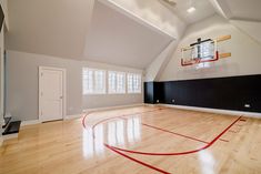 an empty basketball court in the middle of a room with hard wood floors and white walls