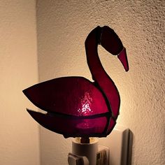 a lamp with a pink glass swan on it's body is lit by a dim light