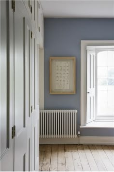 an image of a room with blue walls and white trim on the door, windows, and radiator