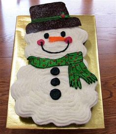 a snowman cake sitting on top of a gold plate covered in icing and frosting