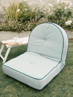 a lawn chair sitting on top of a lush green grass covered field next to a table