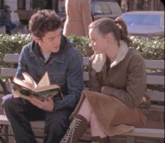 a young man and woman sitting on a bench reading books in front of each other