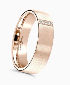 a rose gold wedding ring with diamonds on the inside and outside, against a white background