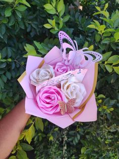 a person holding a pink and white paper flower bouquet with butterflies on it's wings