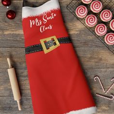 a santa claus apron sitting on top of a wooden table next to cookies and candy