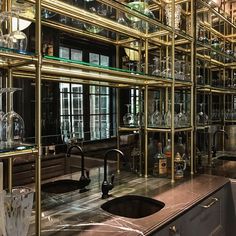 a kitchen counter topped with lots of glass bottles and glasses on top of metal shelves