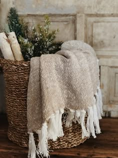 a basket filled with blankets sitting on top of a wooden floor next to a wall