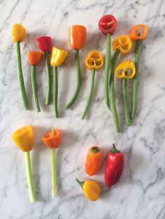 several different types of peppers on a marble counter top with green stems and yellow bell peppers