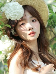 a girl with long hair wearing a straw hat and holding flowers in her left hand