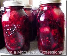 three jars filled with red liquid sitting on top of a counter