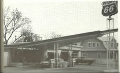 an old gas station with cars parked at it's pump and the sign for route 66