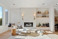 a living room with white walls and wood flooring is furnished with modern furniture, including a fireplace