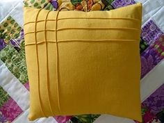 a yellow pillow sitting on top of a colorful quilt