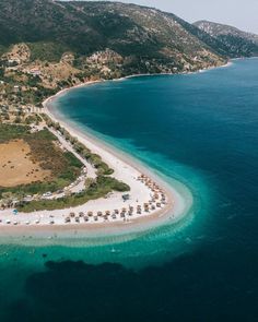 an aerial view of a sandy beach and lagoon in the middle of blue water with umbrellas on it