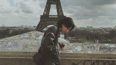 a man standing in front of the eiffel tower looking at his cell phone