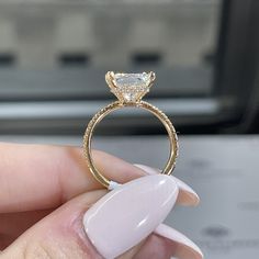 a woman's hand holding an engagement ring in front of her face with a diamond on it