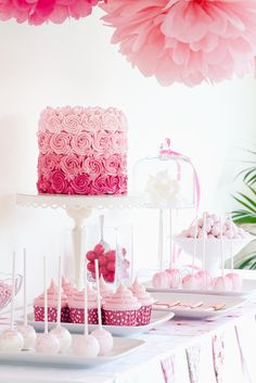 a table topped with lots of cake and cupcakes covered in pink frosting