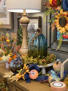 a table topped with lots of different types of vases and flowers next to a lamp