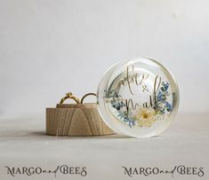 a clear ring with blue and white flowers on it sitting next to a wooden box