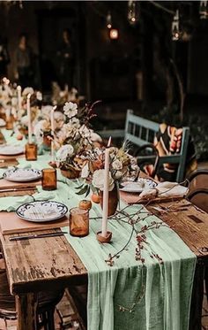 an outdoor table set with plates and candles