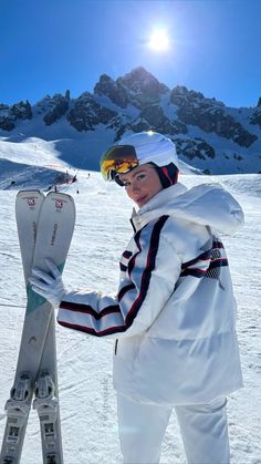 a man standing on top of a snow covered slope holding skis