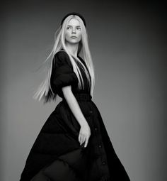 a woman in a long black dress is posing for a magazine cover photo with her hair blowing in the wind