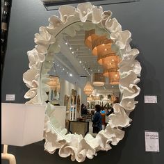 a mirror that is on the wall in front of a lamp and some people looking at it