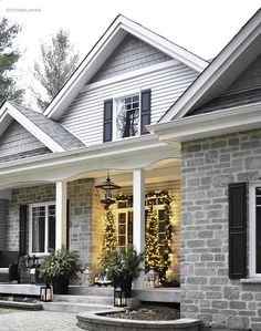 a house decorated for christmas with lights on the front porch and wreaths hanging from the windows