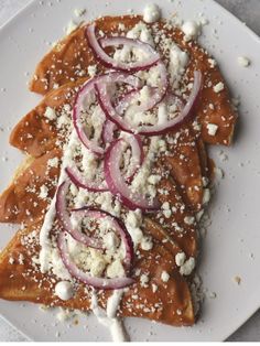 a white plate topped with food covered in cheese and onion slices on top of it