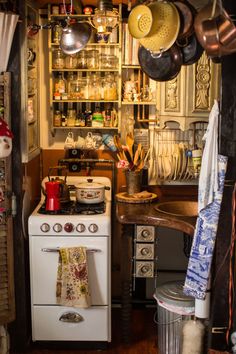 an old fashioned kitchen with pots and pans hanging from the ceiling