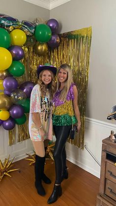 two women standing next to each other in front of balloons