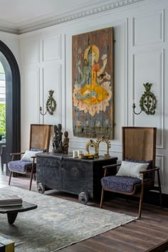 a living room filled with furniture next to a painting on the wall in front of a doorway