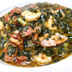 a white bowl filled with shrimp and spinach in a green sauce on top of a table