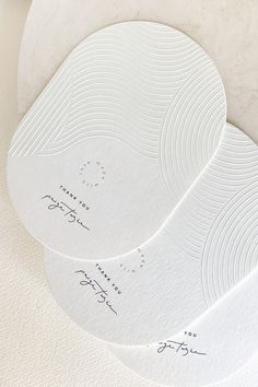 three white circular coasters with handwritten names on them, sitting on a table