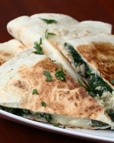 three quesadillas stacked on top of each other on a white plate with green garnishes