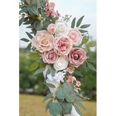 a bouquet of pink and white flowers on top of a wooden pole with greenery