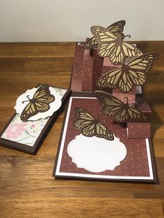 some cards with butterflies on them sitting on a wooden table next to a card holder