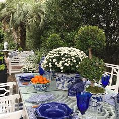 a blue and white table setting with flowers in vases, oranges and plates