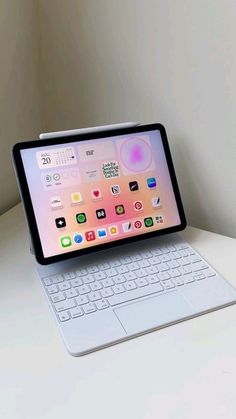 an ipad and keyboard sitting on top of a white desk next to each other in front of a wall