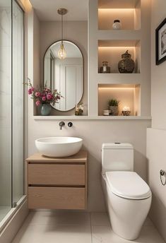 a white toilet sitting next to a sink in a bathroom under a large round mirror