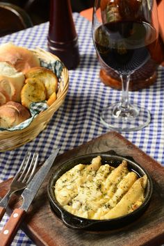 a table topped with bread and wine next to a basket filled with breadsticks