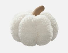 a white stuffed pumpkin with a wooden top hanging from it's side on a gray background