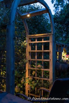 a wooden trellis in the middle of a garden at night