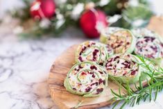 an assortment of food items on a wooden platter with greenery and red baubles in the background