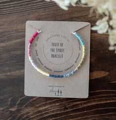 the fruit of the spirit bracelet is packaged on a card with flowers in the background