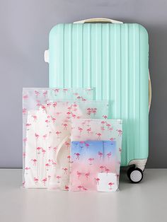 three pieces of luggage sitting next to each other on a white table with pink and blue flamingos