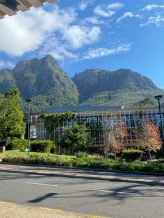 a building with mountains in the background near a street and lampposts on both sides