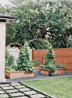 an outdoor garden with wooden planters and brick walkway leading to the back yard area